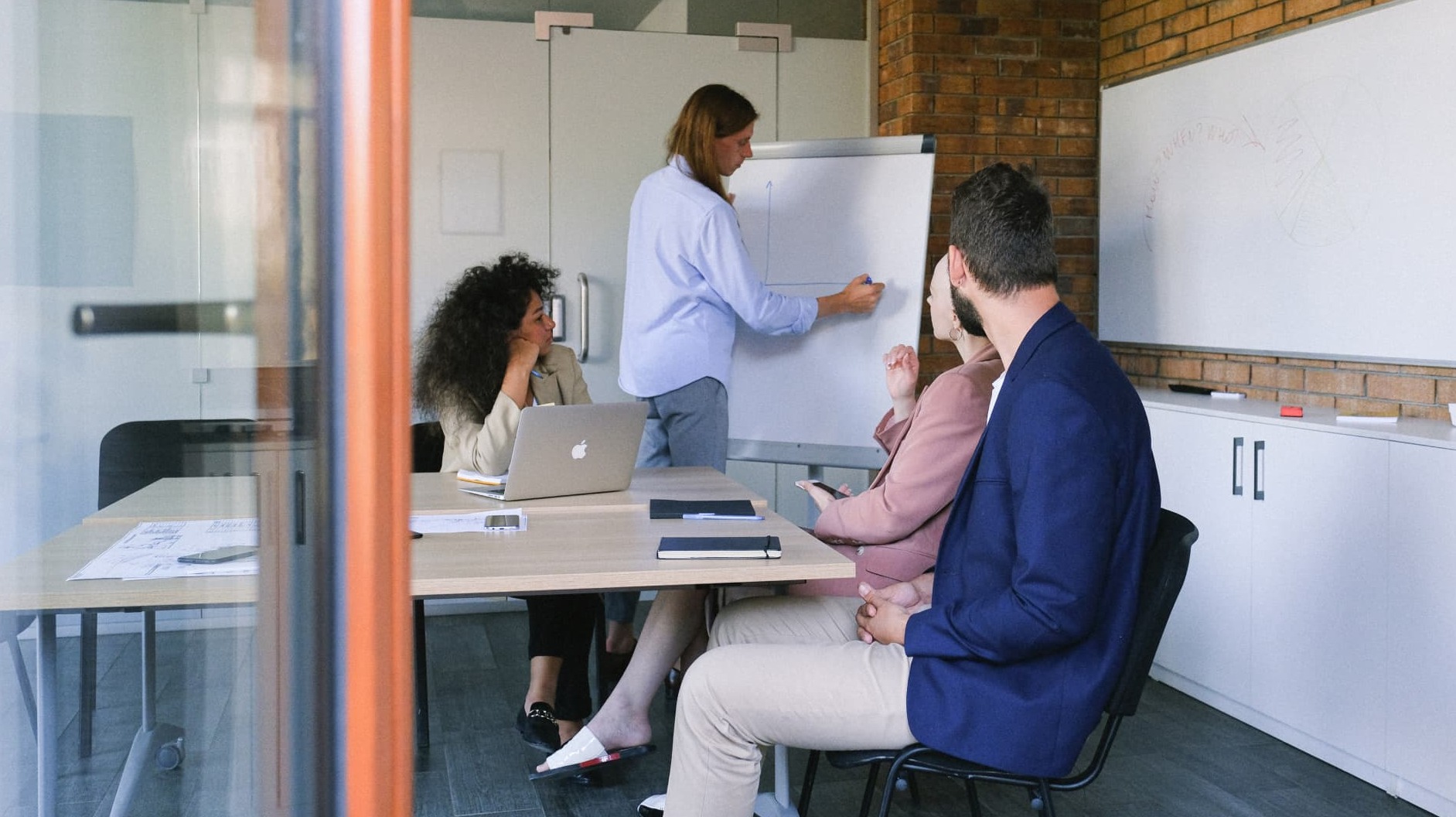 Team of four people collaborating around a whiteboard in an office environment